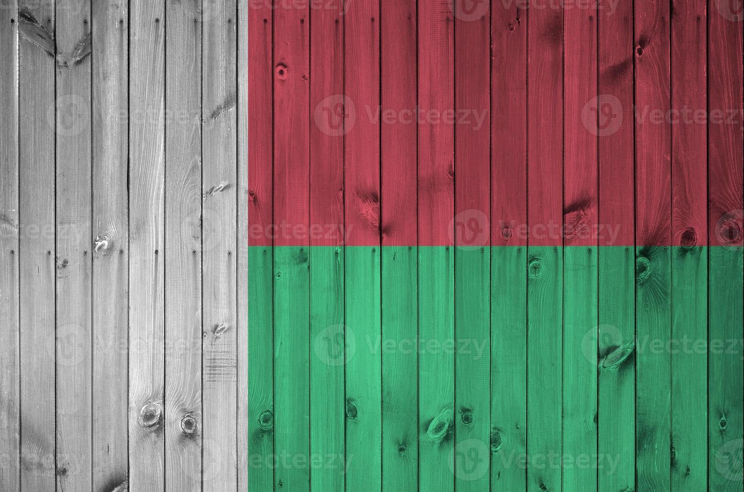 Madagascar flag depicted in bright paint colors on old wooden wall. Textured banner on rough background photo