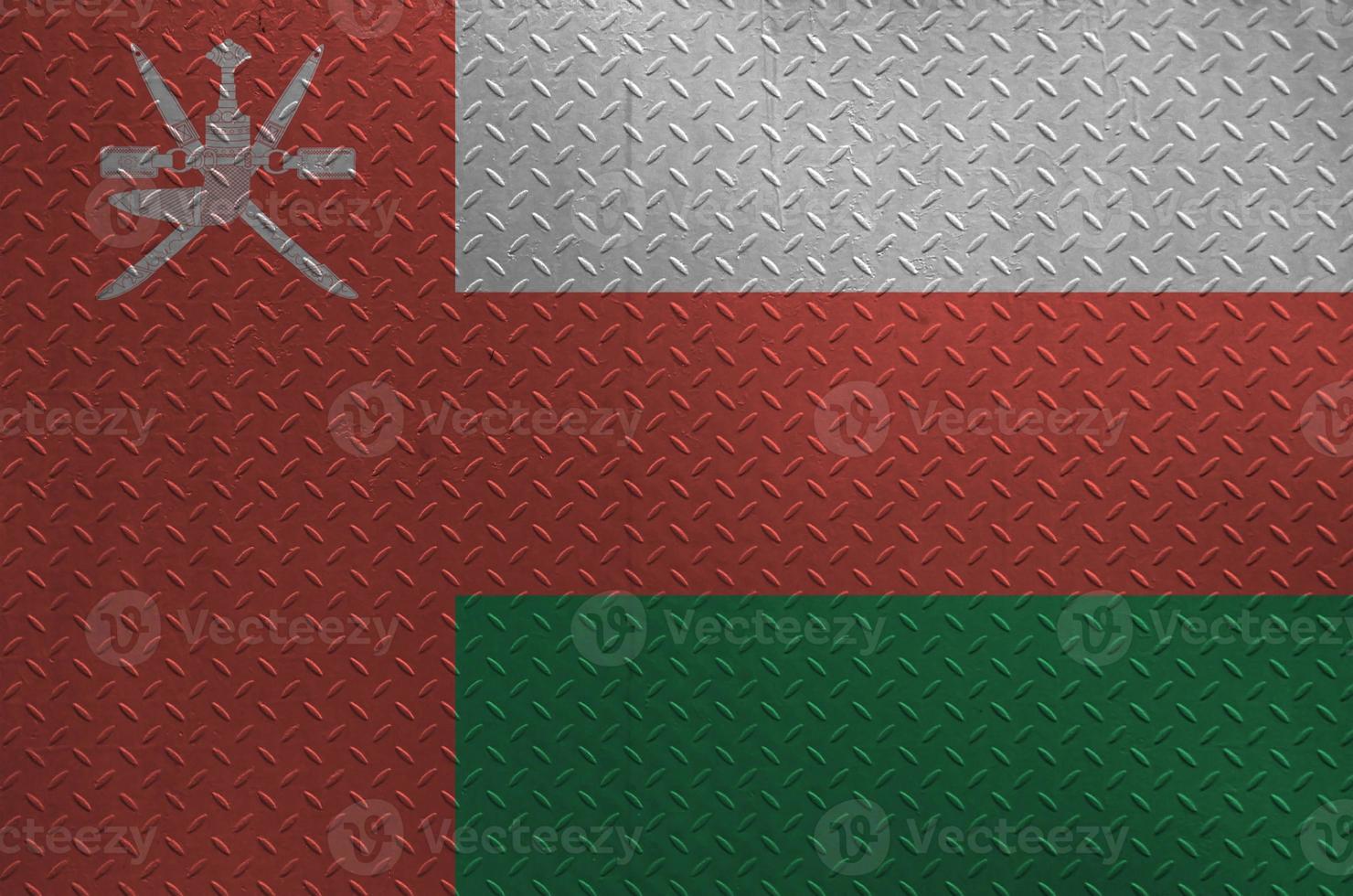 Oman flag depicted in paint colors on old brushed metal plate or wall closeup. Textured banner on rough background photo