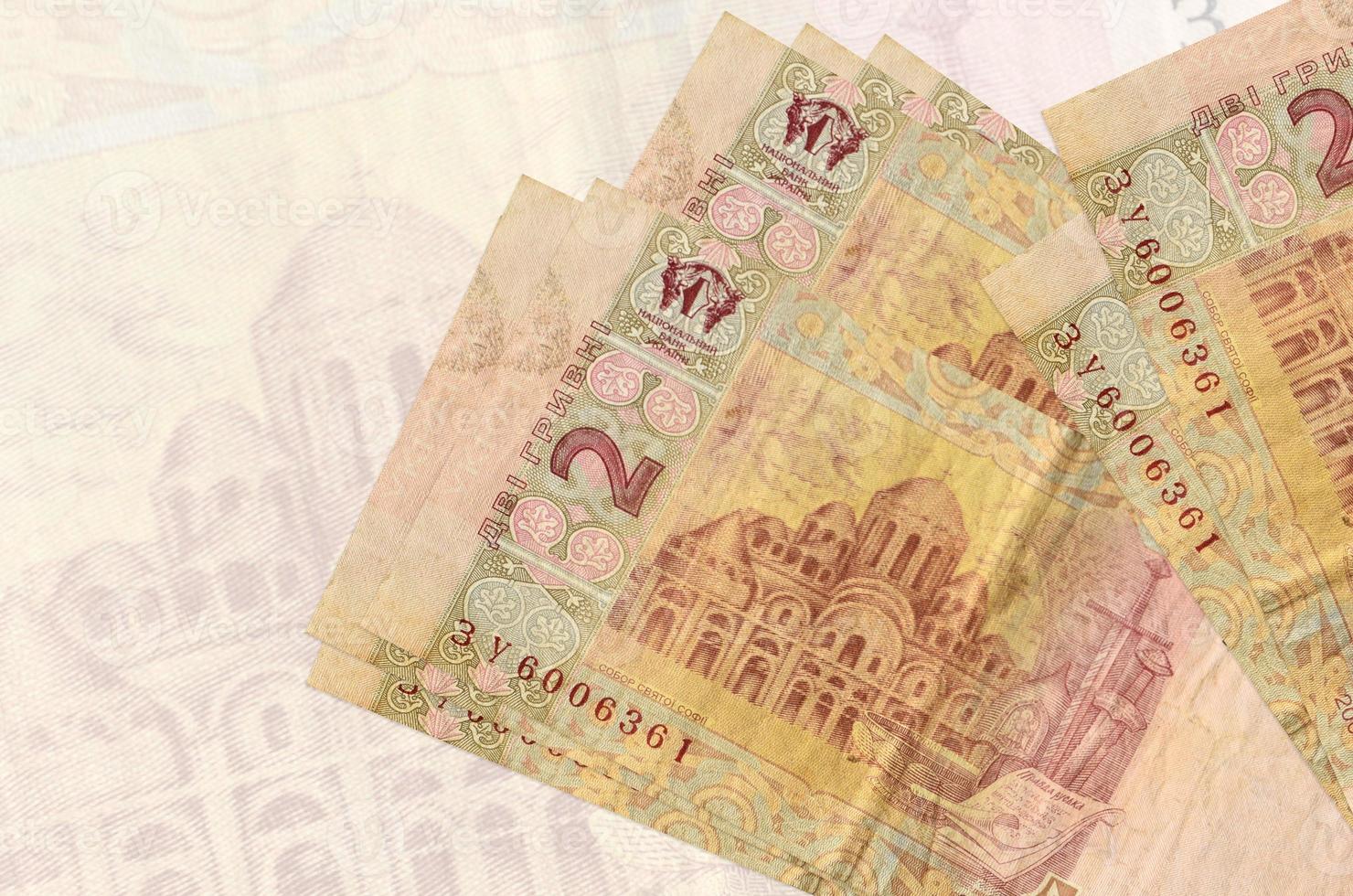2 Ukrainian hryvnias bills lies in stack on background of big semi-transparent banknote. Abstract presentation of national currency photo