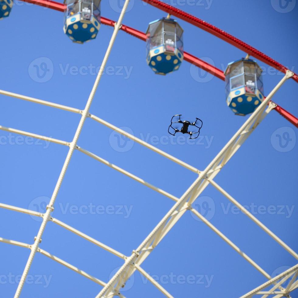 Drone take off from land and flying for take photo front of ferris wheel