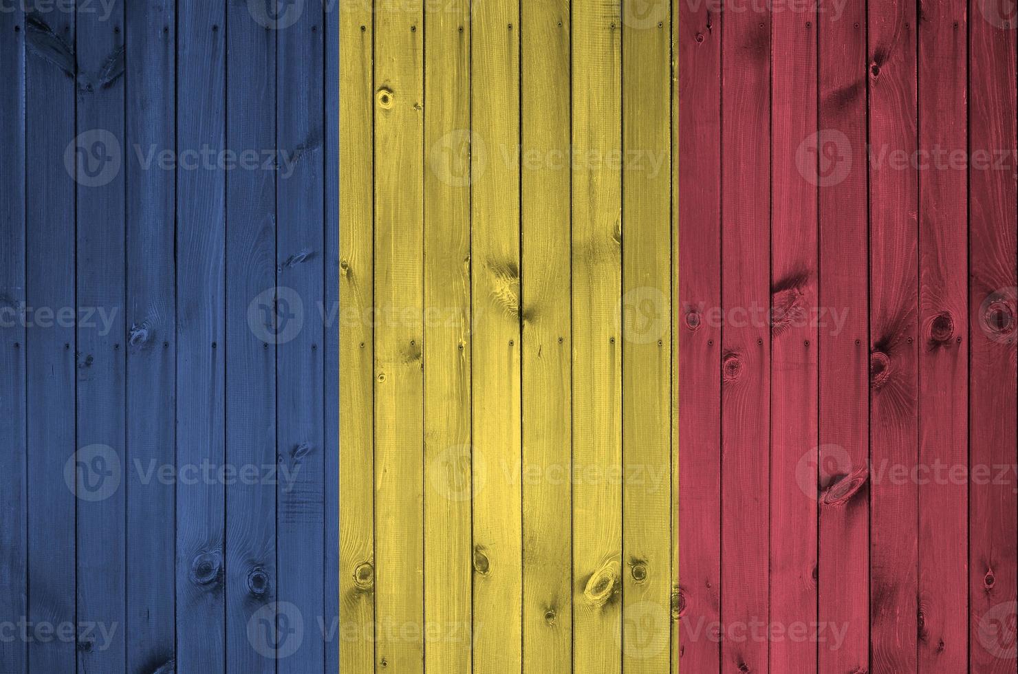 Romania flag depicted in bright paint colors on old wooden wall. Textured banner on rough background photo