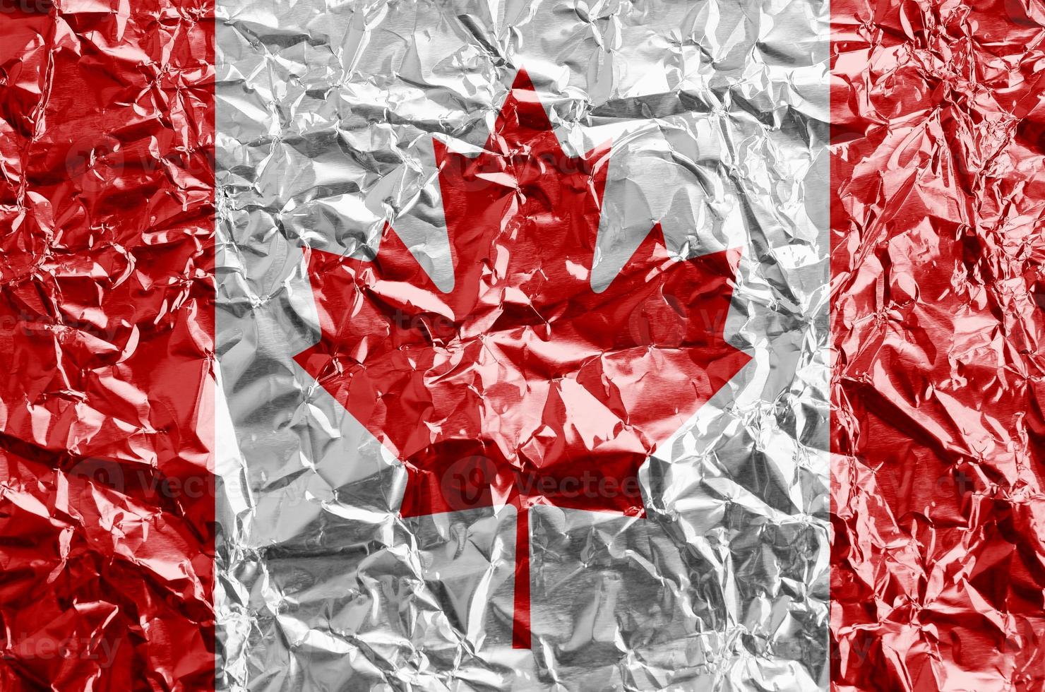 Canada flag depicted in paint colors on shiny crumpled aluminium foil closeup. Textured banner on rough background photo