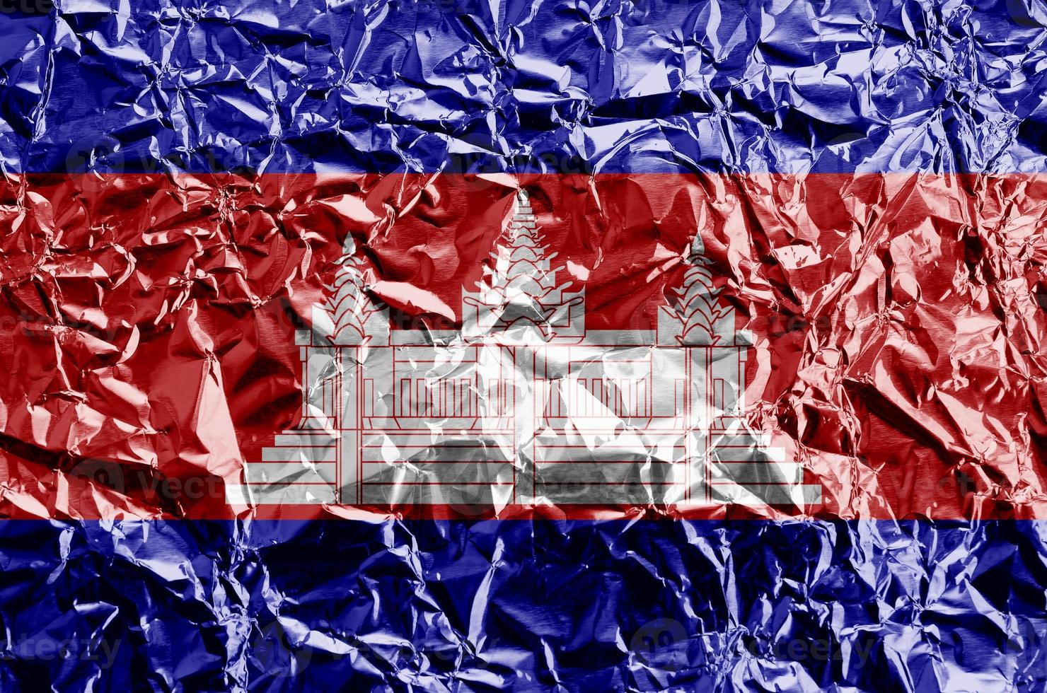 Cambodia flag depicted in paint colors on shiny crumpled aluminium foil closeup. Textured banner on rough background photo