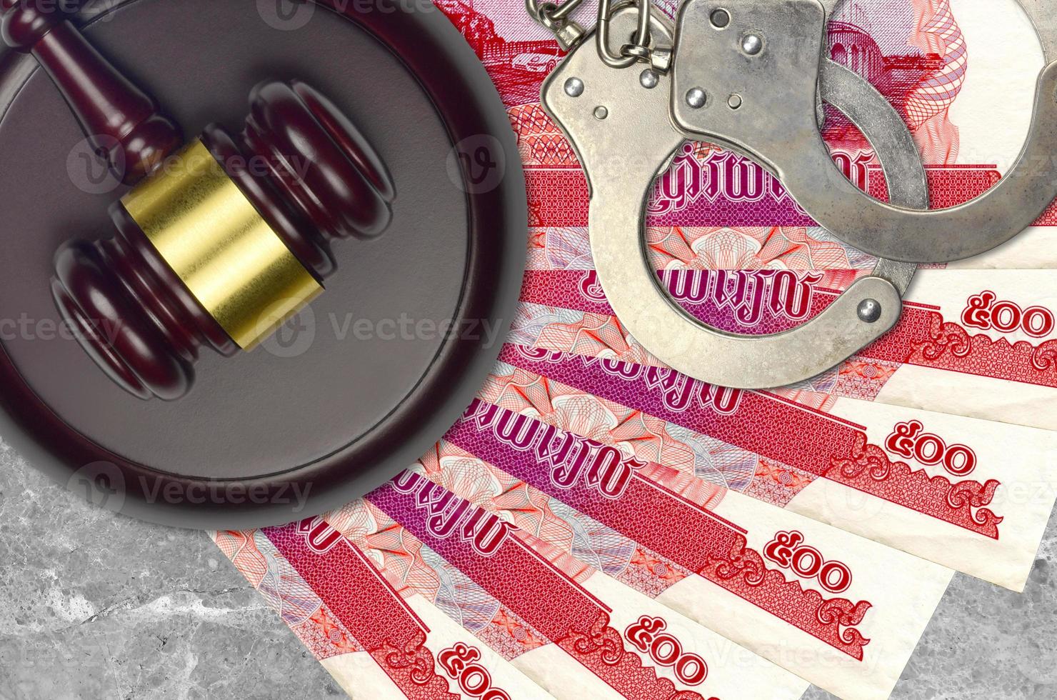 500 Cambodian riels bills and judge hammer with police handcuffs on court desk. Concept of judicial trial or bribery. Tax avoidance photo