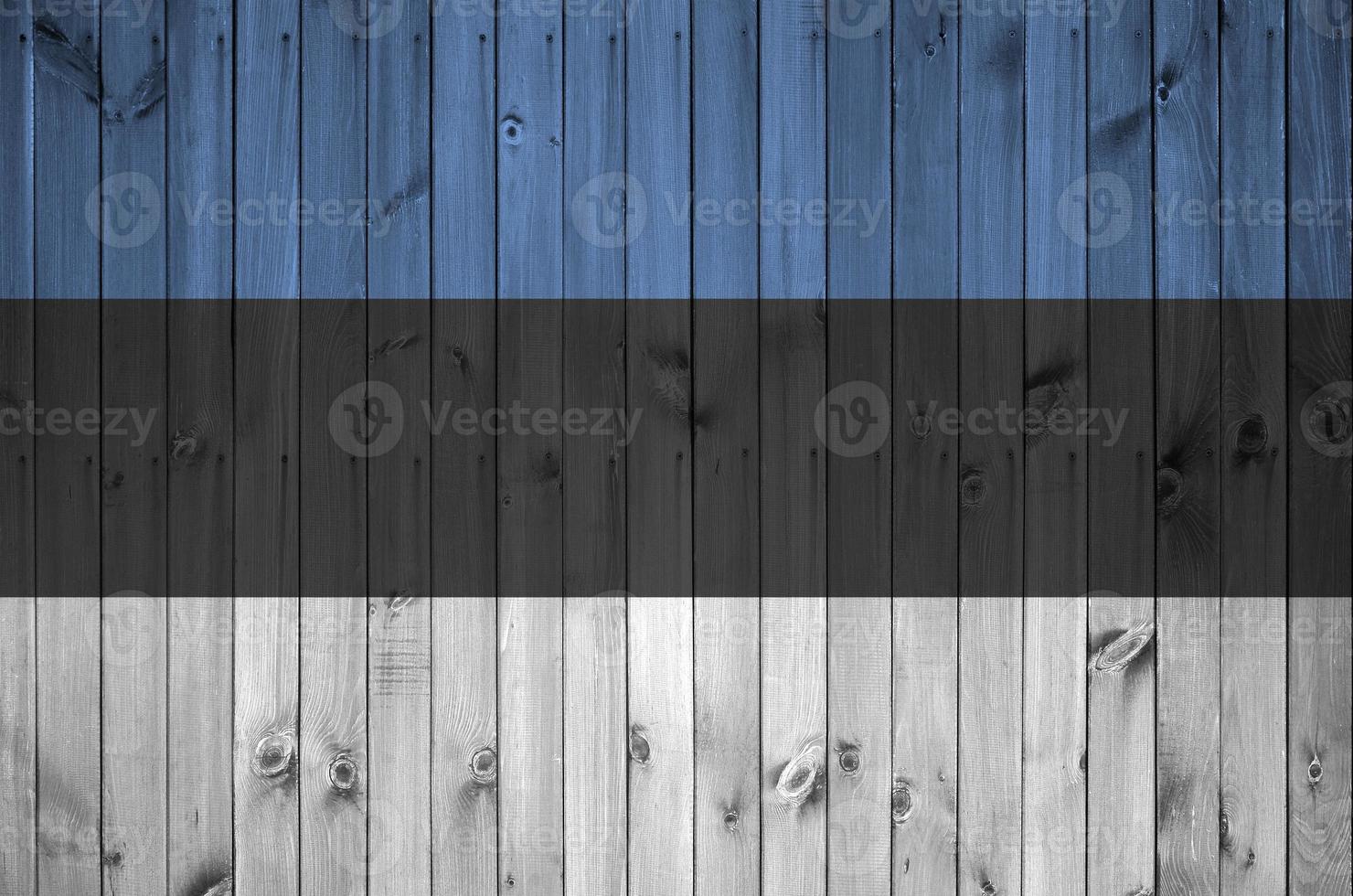 Estonia flag depicted in bright paint colors on old wooden wall. Textured banner on rough background photo