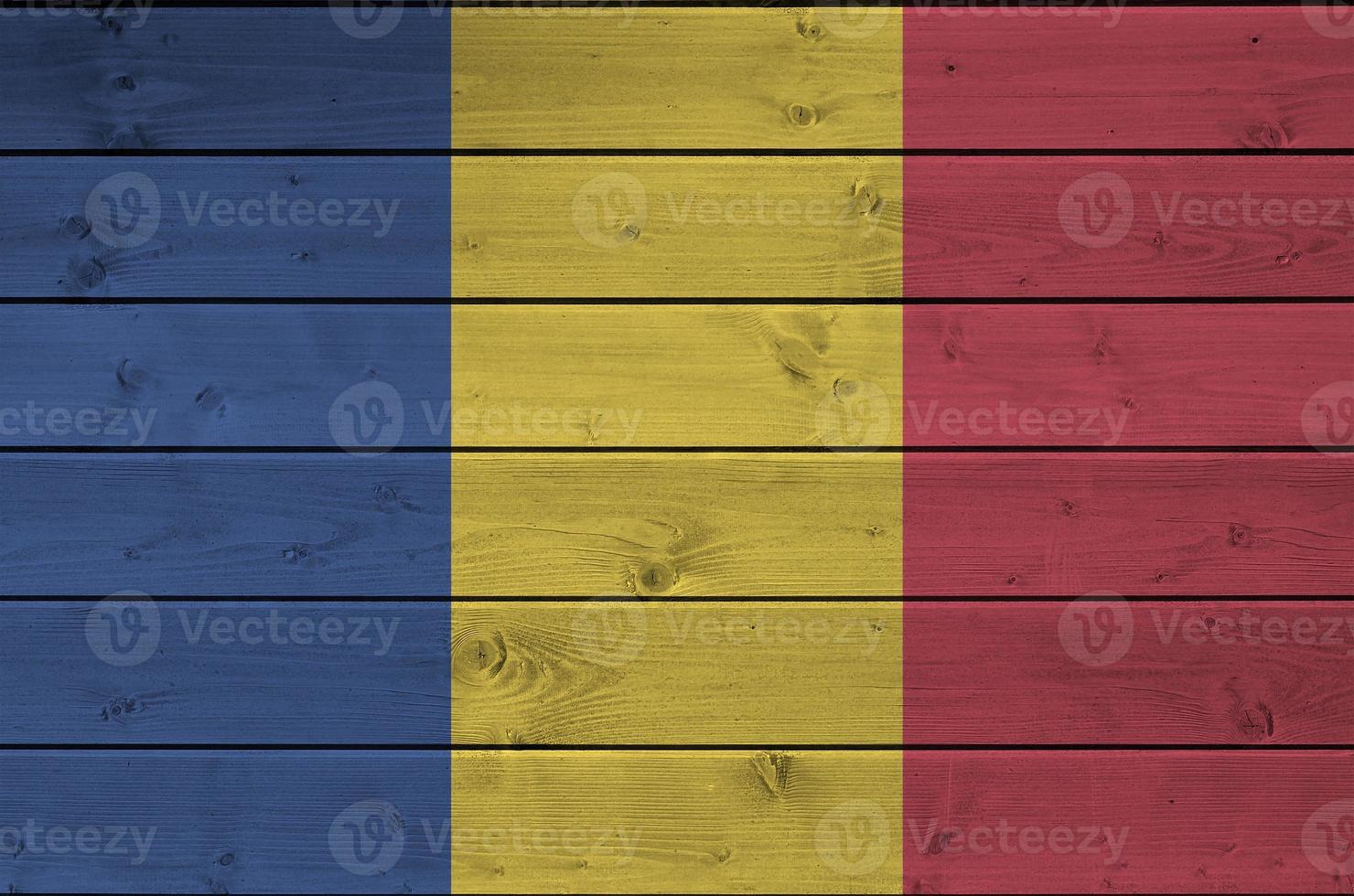 Romania flag depicted in bright paint colors on old wooden wall. Textured banner on rough background photo