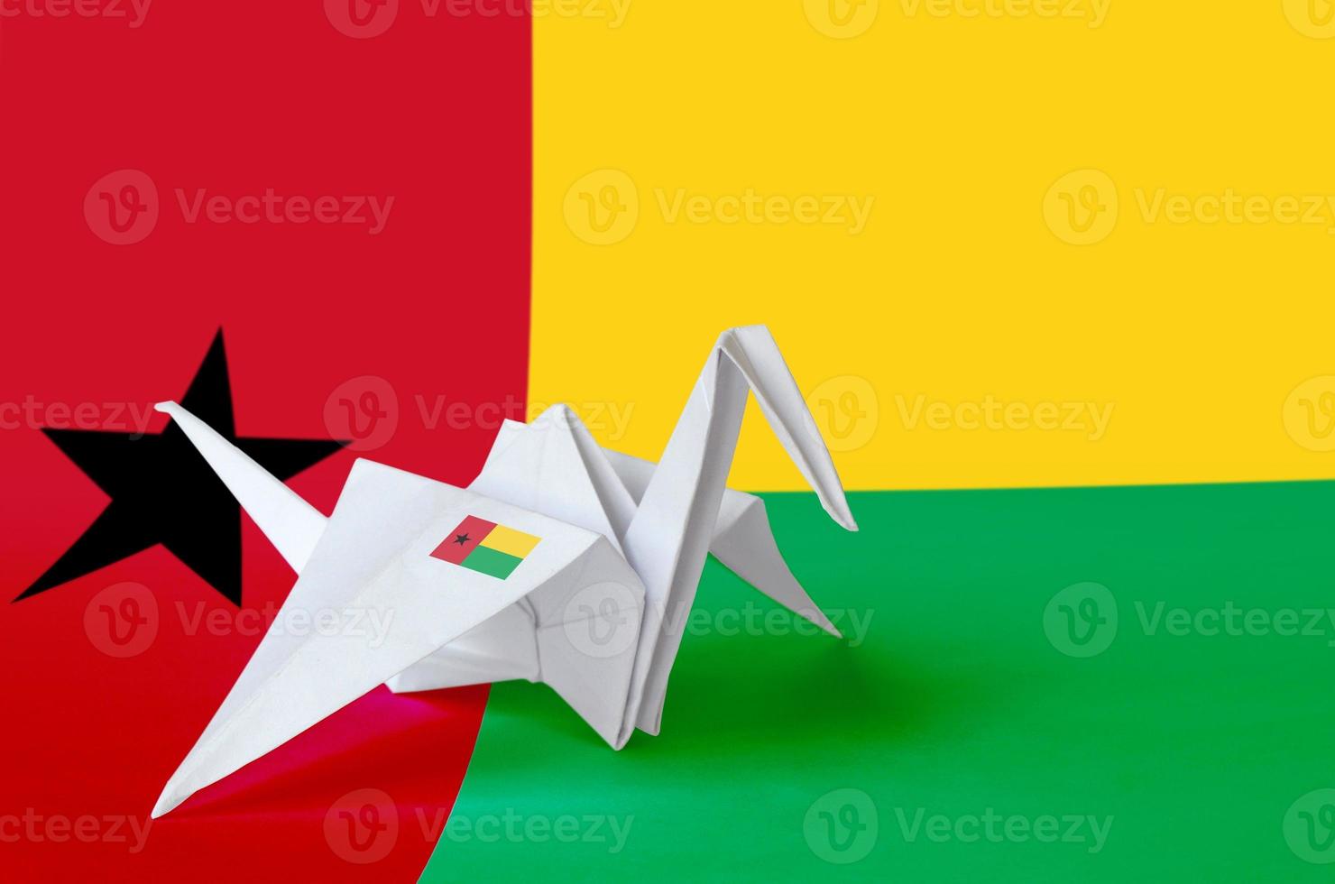 Guinea Bissau flag depicted on paper origami crane wing. Handmade arts concept photo