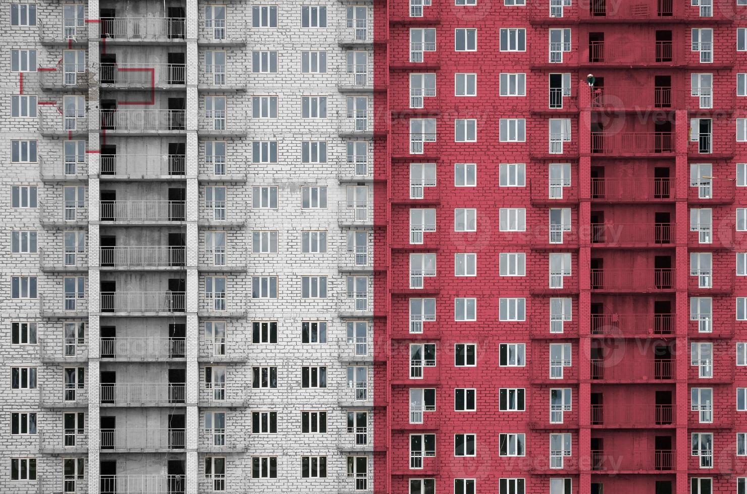 Malta flag depicted in paint colors on multi-storey residental building under construction. Textured banner on brick wall background photo