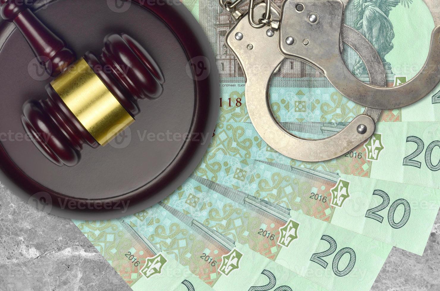 20 Ukrainian hryvnias bills and judge hammer with police handcuffs on court desk. Concept of judicial trial or bribery. Tax avoidance photo