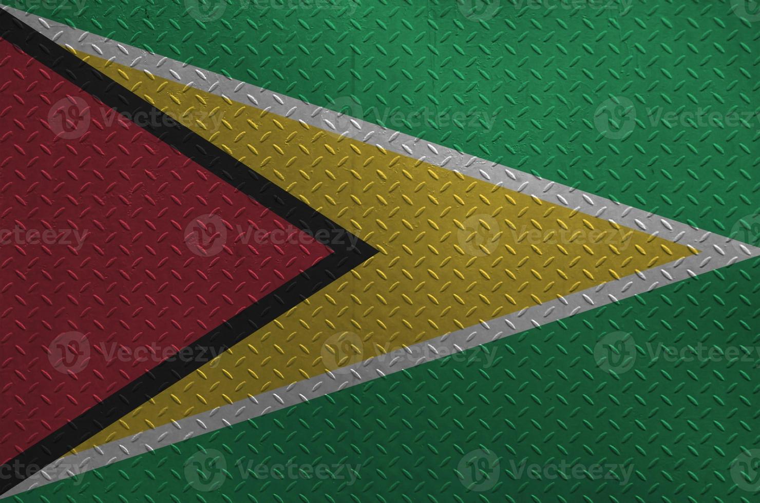 Guyana flag depicted in paint colors on old brushed metal plate or wall closeup. Textured banner on rough background photo