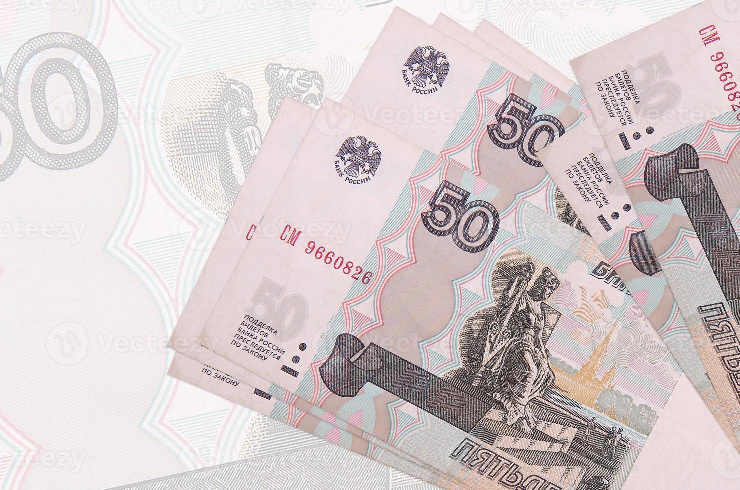 50 russian rubles bills lies in stack on background of big semi-transparent banknote. Abstract presentation of national currency photo