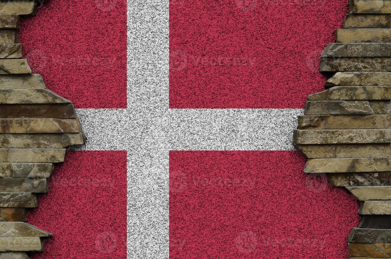 Denmark flag depicted in paint colors on old stone wall closeup. Textured banner on rock wall background photo