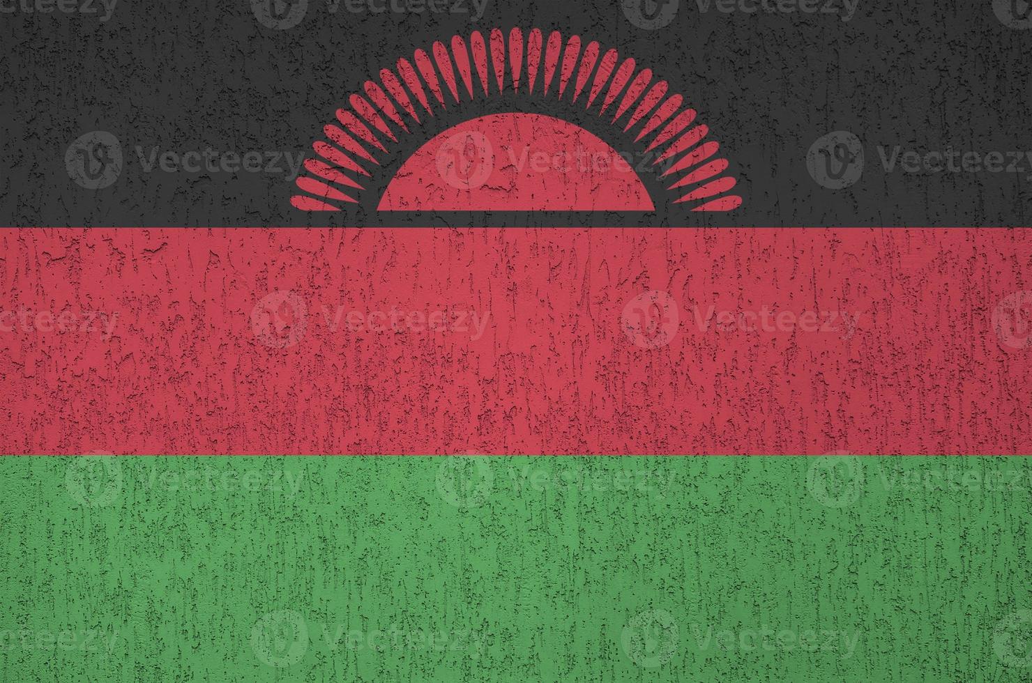 Malawi flag depicted in bright paint colors on old relief plastering wall. Textured banner on rough background photo