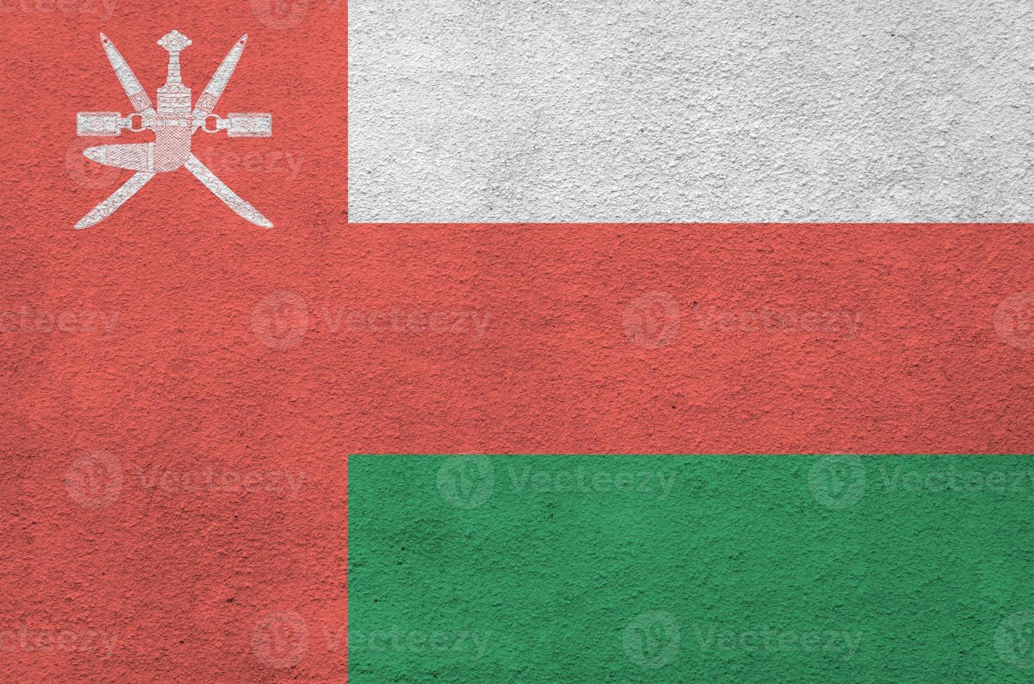 Oman flag depicted in bright paint colors on old relief plastering wall. Textured banner on rough background photo