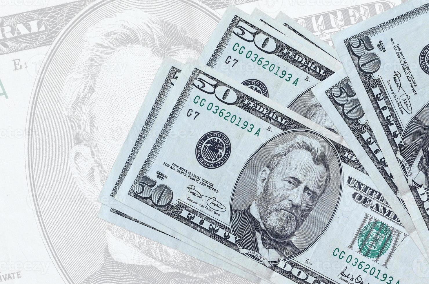 50 US dollars bills lies in stack on background of big semi-transparent banknote. Abstract presentation of national currency photo