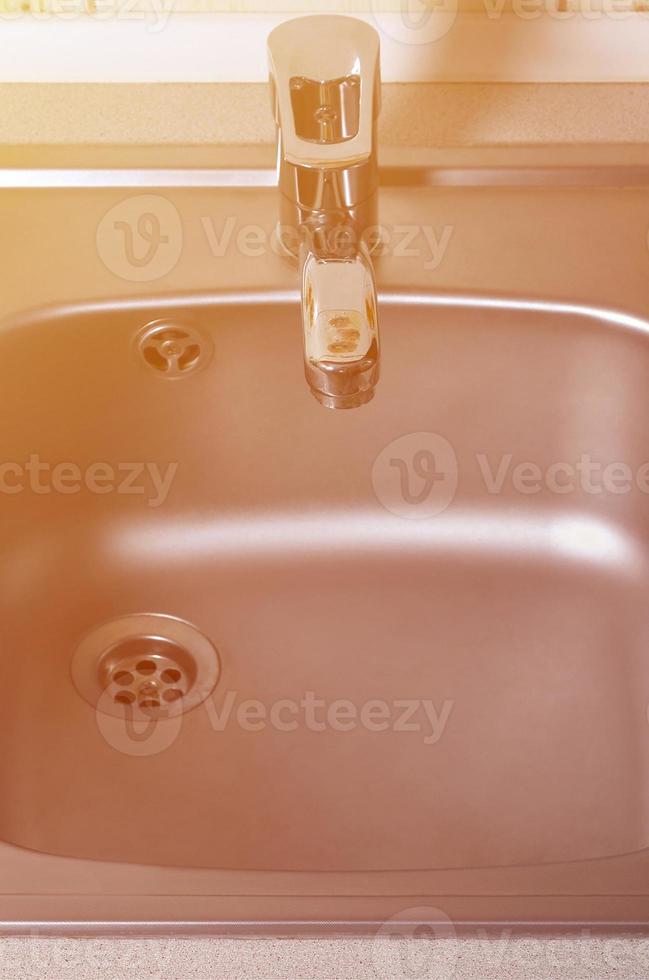 Empty clean silvery kitchen sink and water faucet close up photo