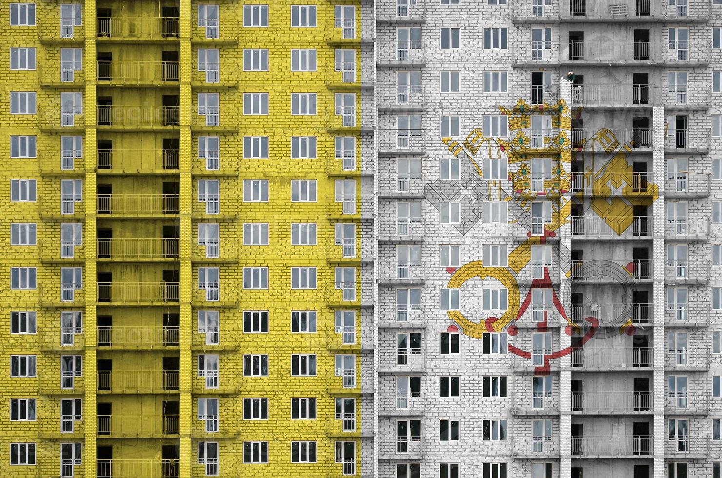 Vatican City State flag depicted in paint colors on multi-storey residental building under construction. Textured banner on brick wall background photo