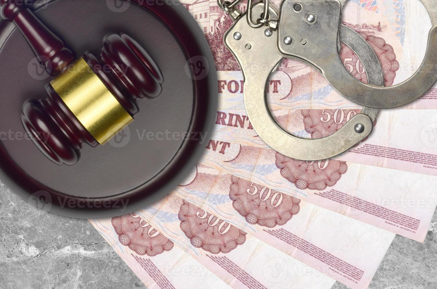 500 Hungarian forint bills and judge hammer with police handcuffs on court desk. Concept of judicial trial or bribery. Tax avoidance photo