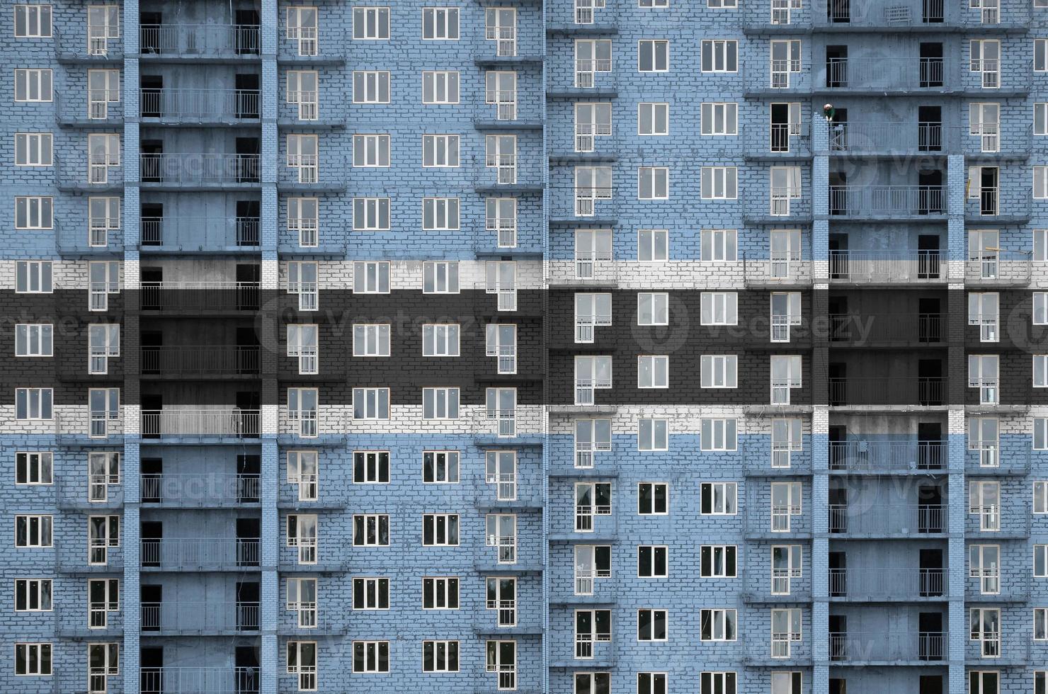 Botswana flag depicted in paint colors on multi-storey residental building under construction. Textured banner on brick wall background photo