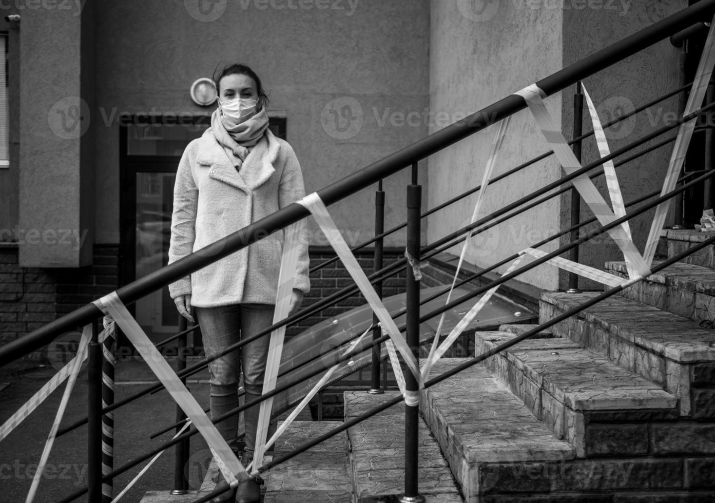 Photo of a girl in a mask. Standing on the street with danger warning tapes.