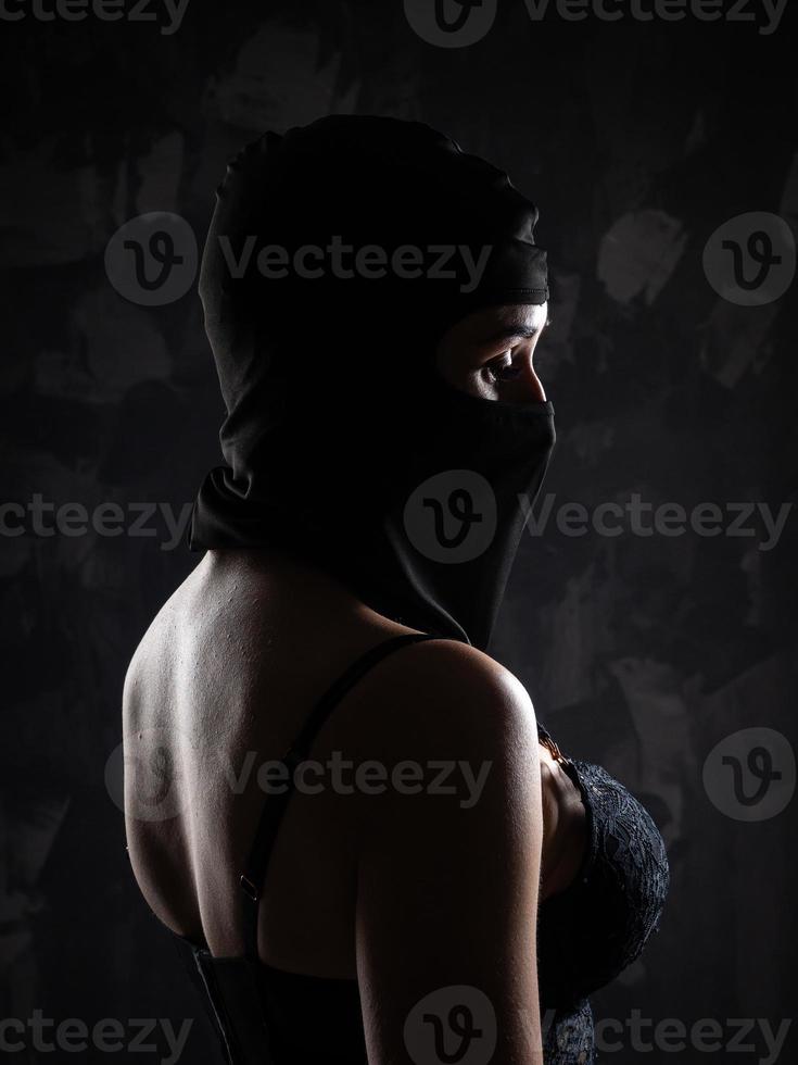 Portrait of a girl in a black balaclava and a black bra. photo