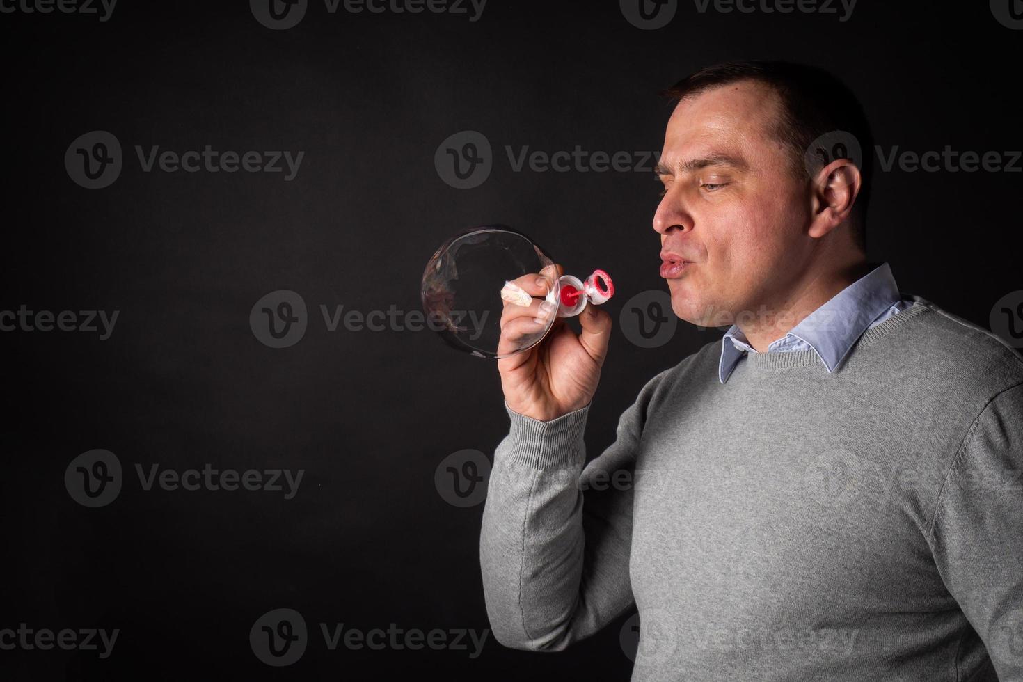 handsome man in a suit is blowing soap bubbles. photo