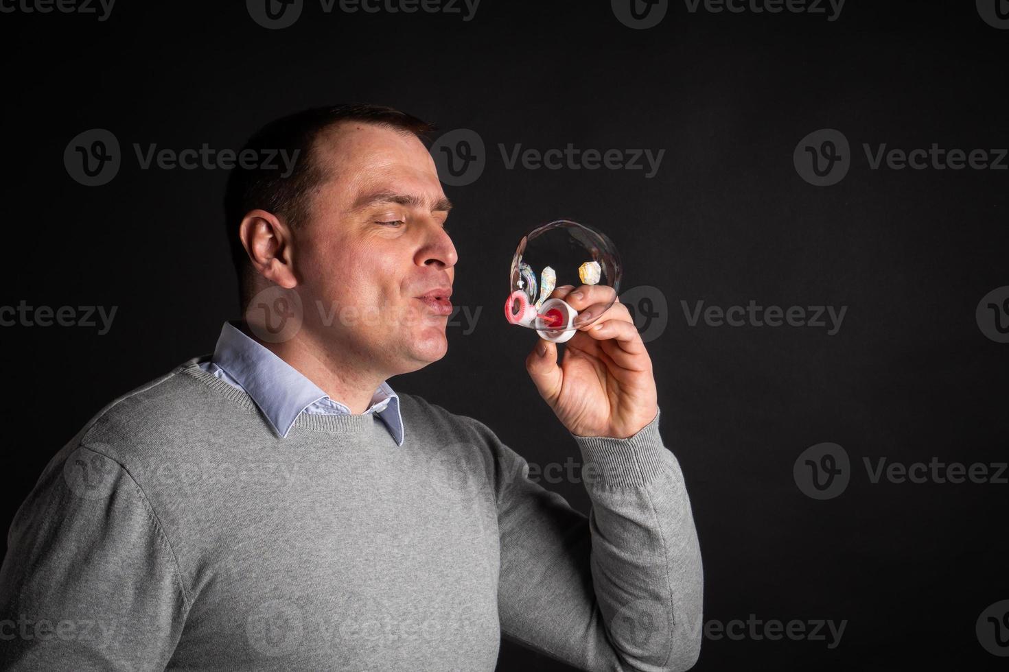 handsome man in a suit is blowing soap bubbles. photo