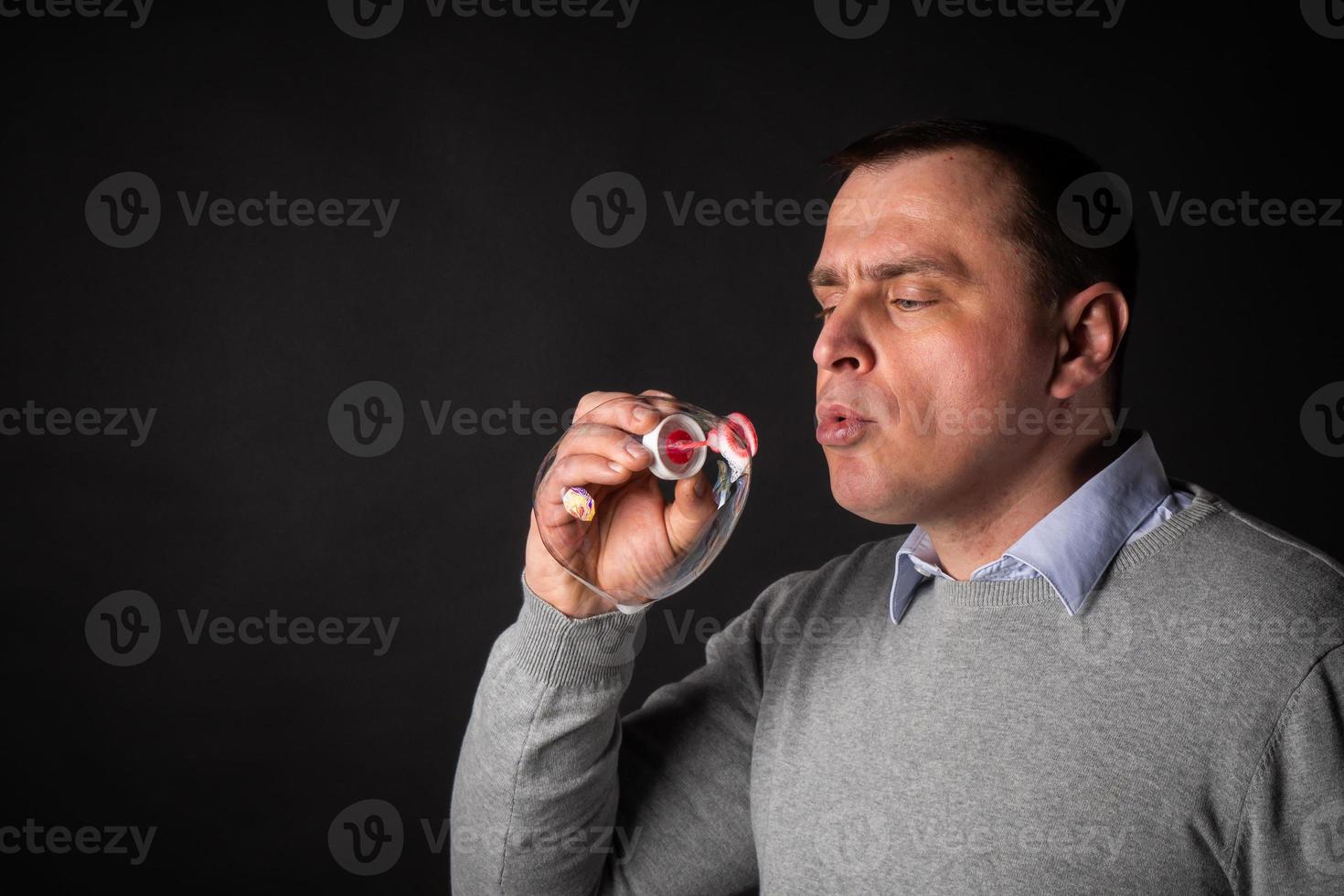 handsome man in a suit is blowing soap bubbles. photo