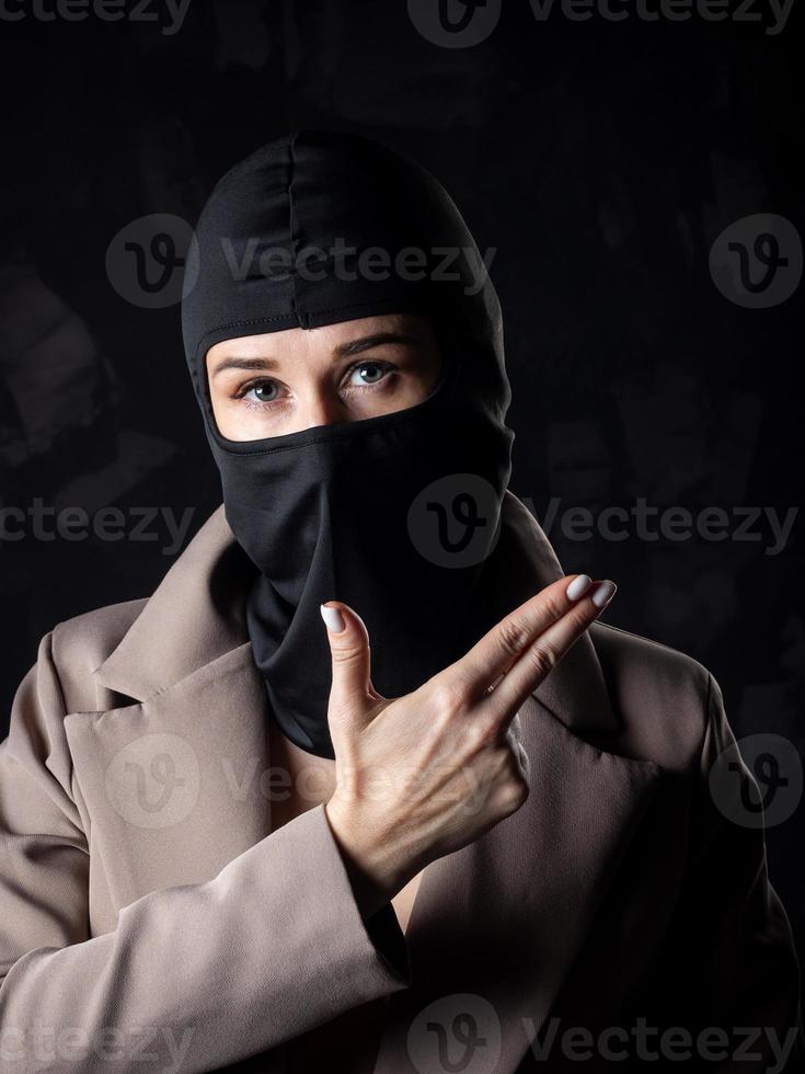 Portrait of a girl in a black balaclava and beige coat. photo