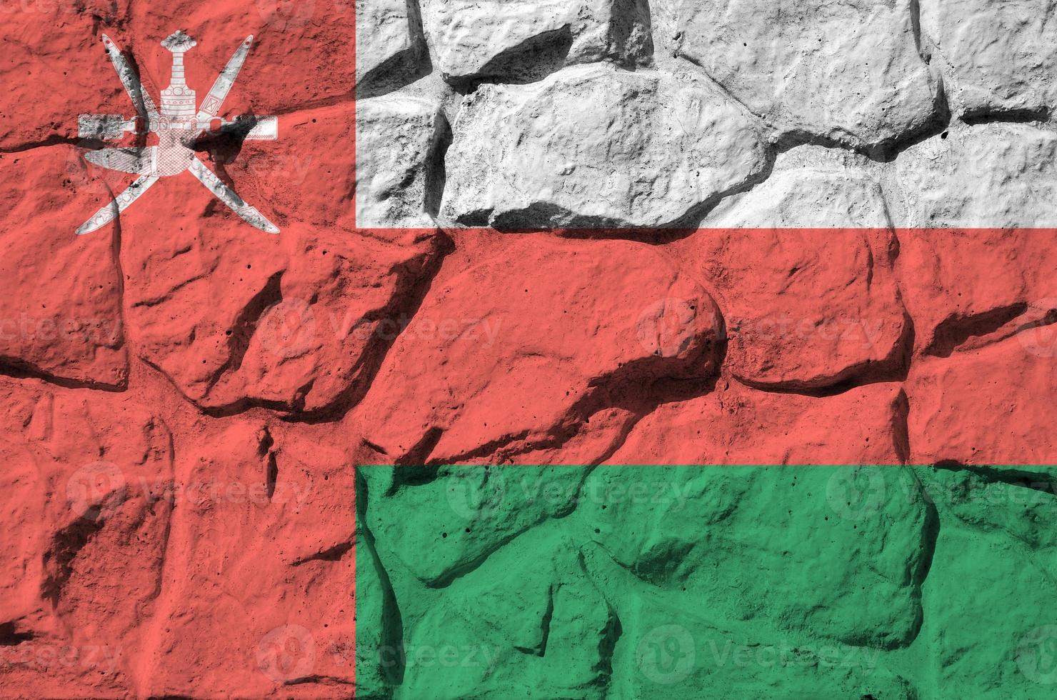 Oman flag depicted in paint colors on old stone wall closeup. Textured banner on rock wall background photo