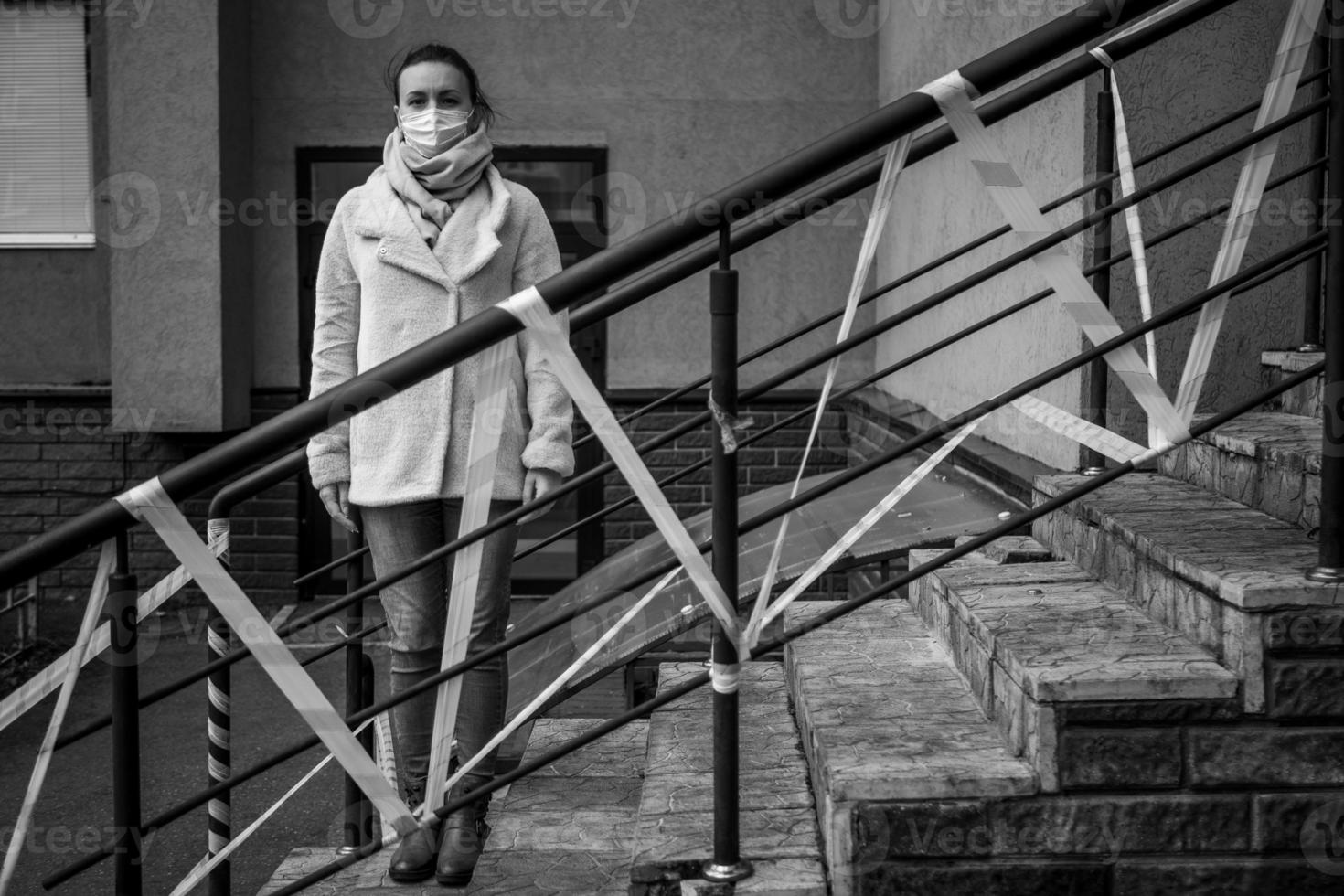 Photo of a girl in a mask. Standing on the street with danger warning tapes.