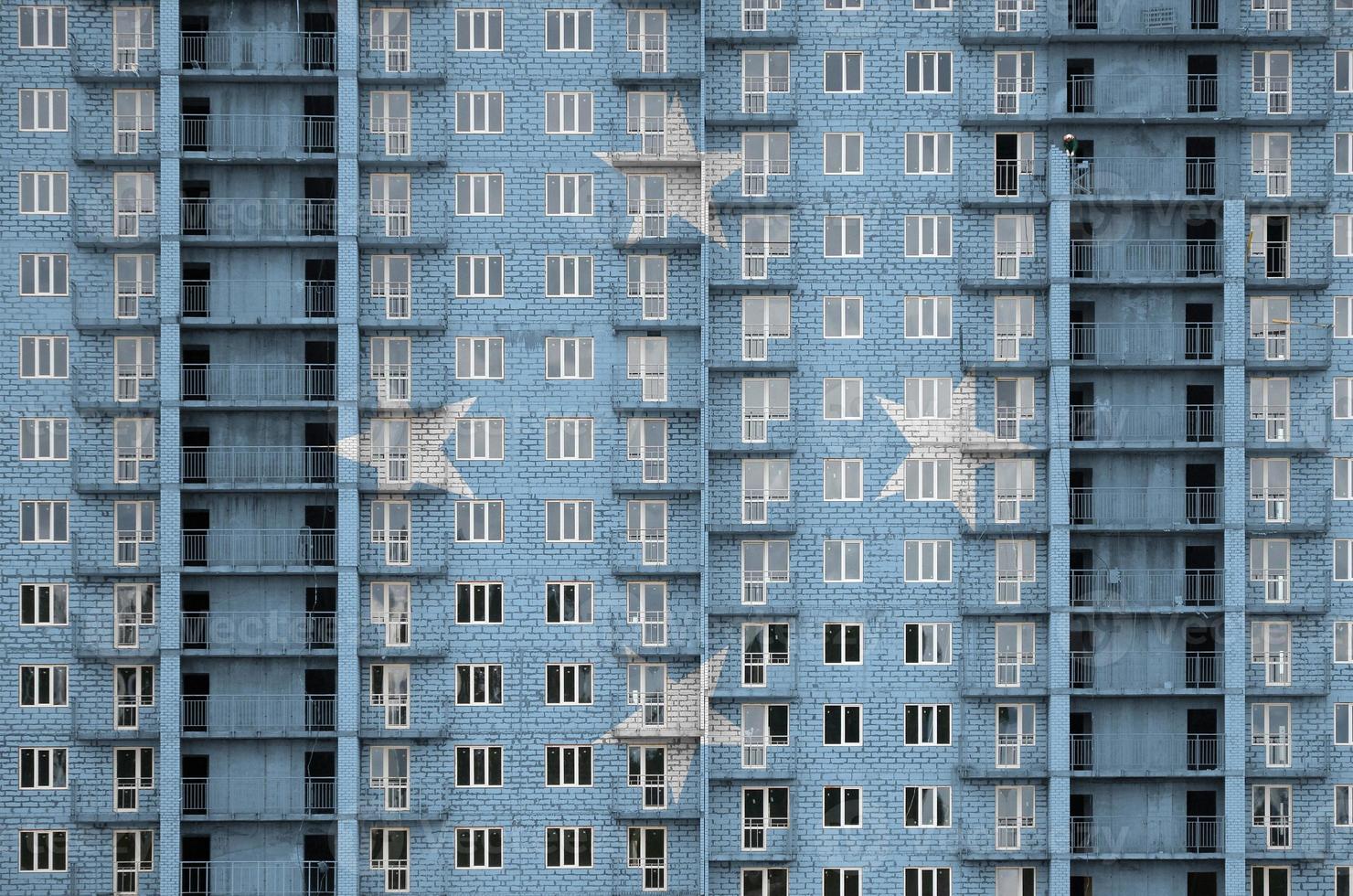 Micronesia flag depicted in paint colors on multi-storey residental building under construction. Textured banner on brick wall background photo