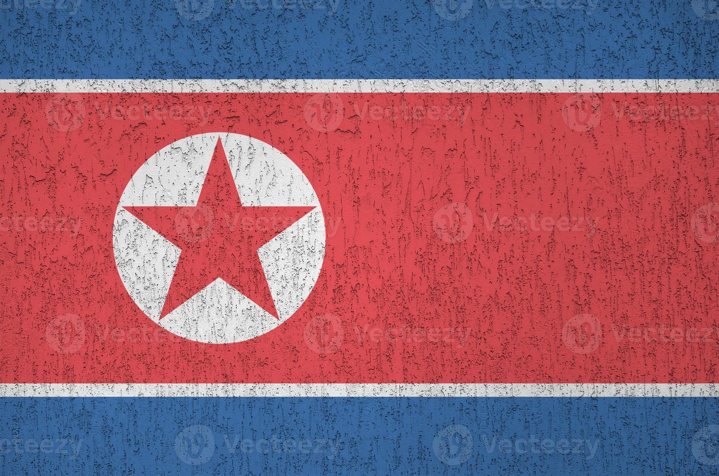 North Korea flag depicted in bright paint colors on old relief plastering wall. Textured banner on rough background photo