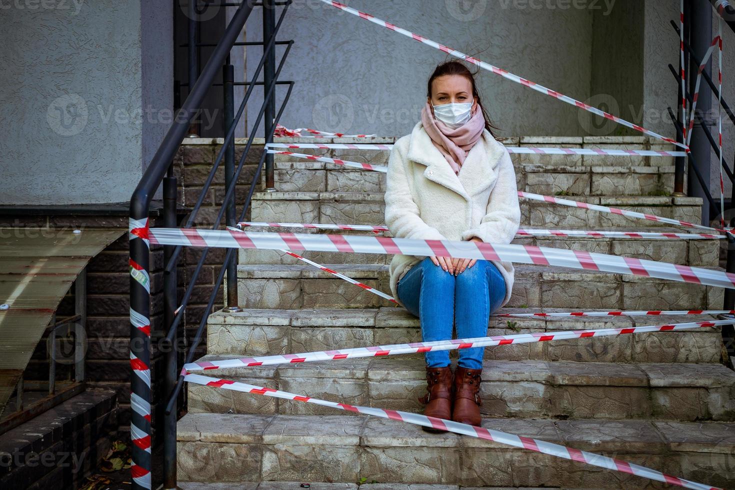 foto de una chica con una máscara. sentado en la calle con cintas de advertencia de peligro.