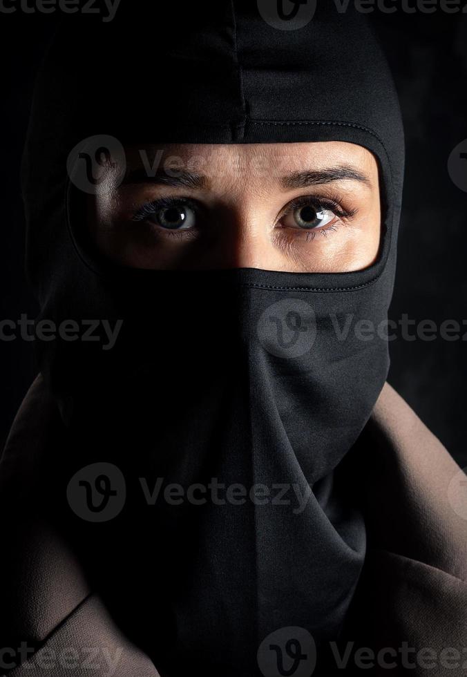 Portrait of a girl in a black balaclava and beige coat. photo