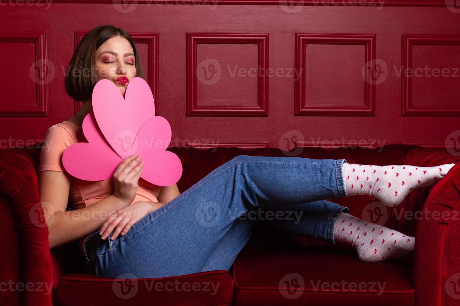 Women with closed eyes on couch holding three heart shapes photo