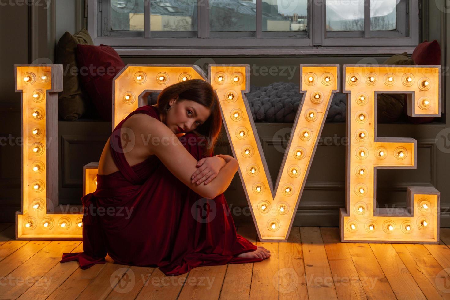 mujer con vestido rojo haciendo la letra o frente a cartas de amor foto