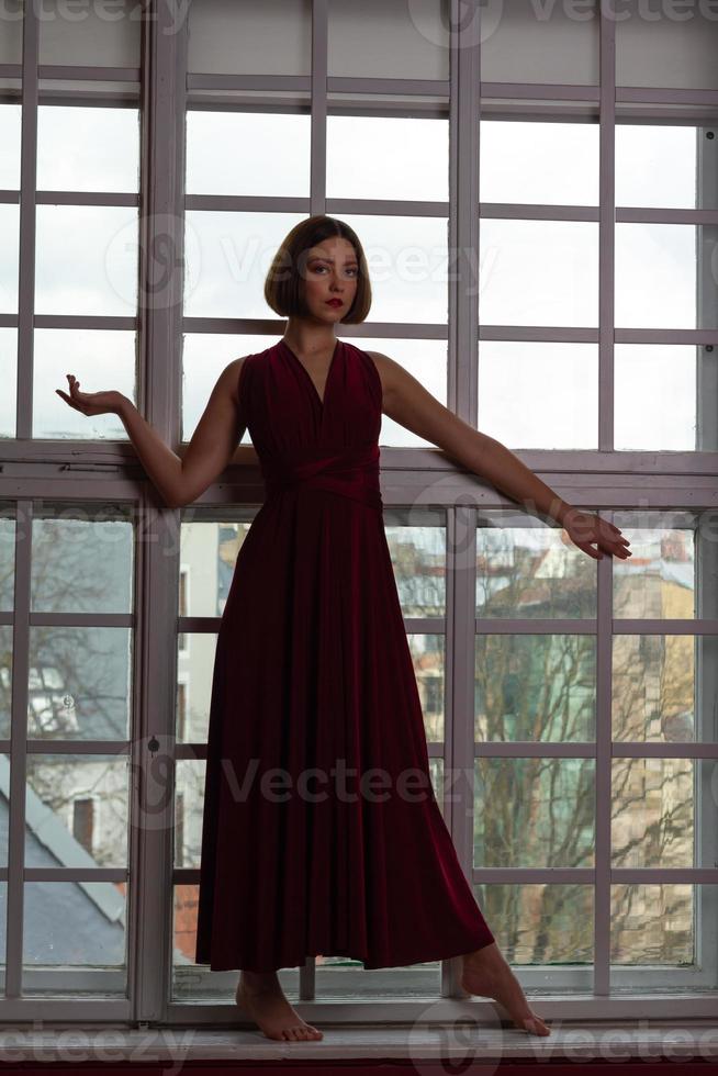 mujer vestida de rojo con el brazo extendido frente a la ventana foto