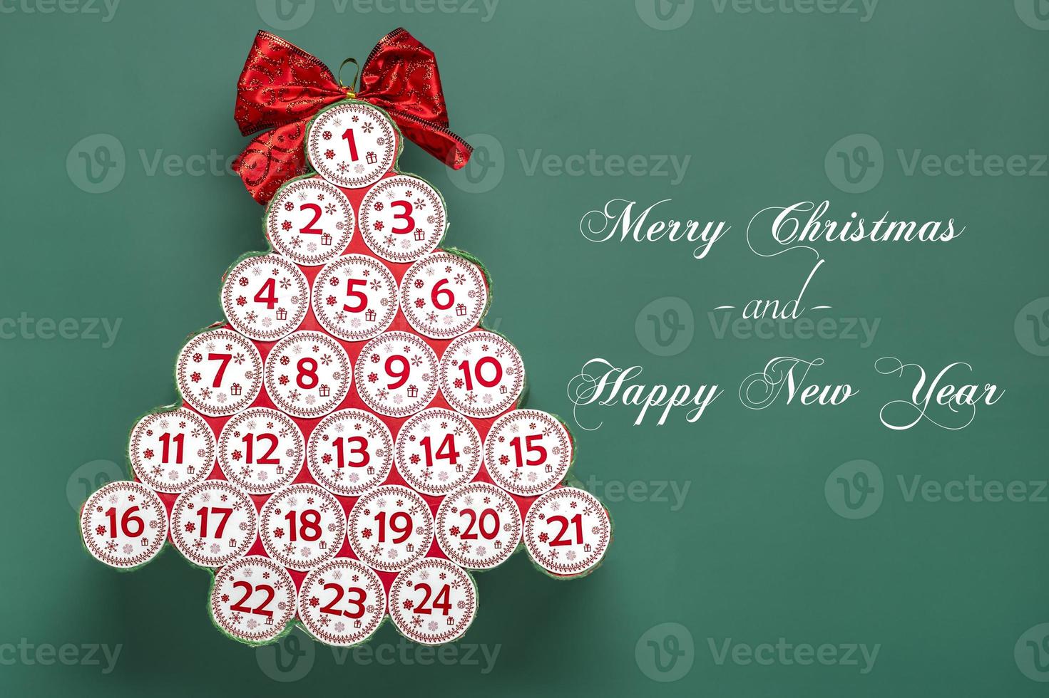 Advent calendar in shape of Christmas tree with numbers and ribbon instead of star, bokeh light on green background Xmas advent calendar concept Top view Flat lay photo