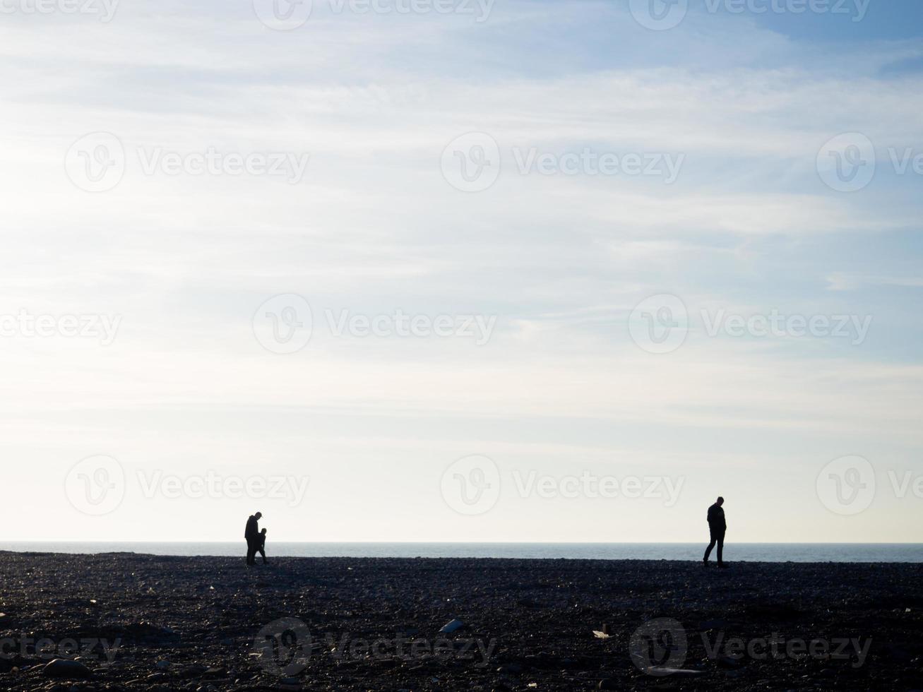 People on the spring pebble beach at sunset. Vacation on the beach. Rest on the sea. Rocky shore. Pebble beach. photo