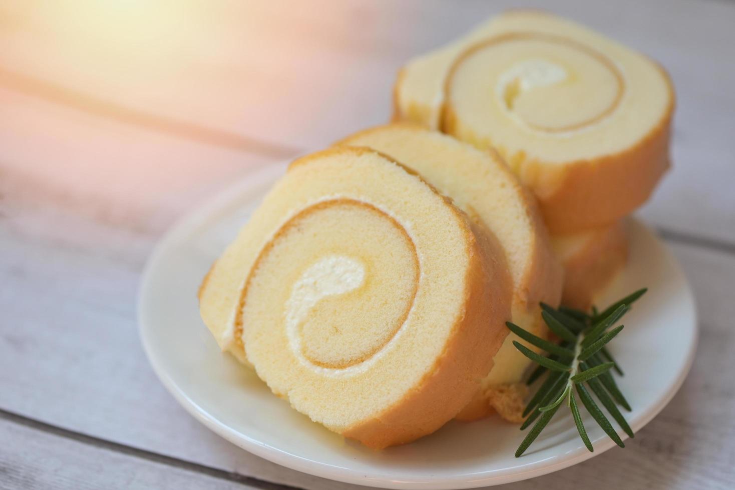 Cake roll on plate cake with rosemary on table, sponge cake roll slices sweets dessert cream roll vanilla snacks and food concept - Swiss Roll Cake photo