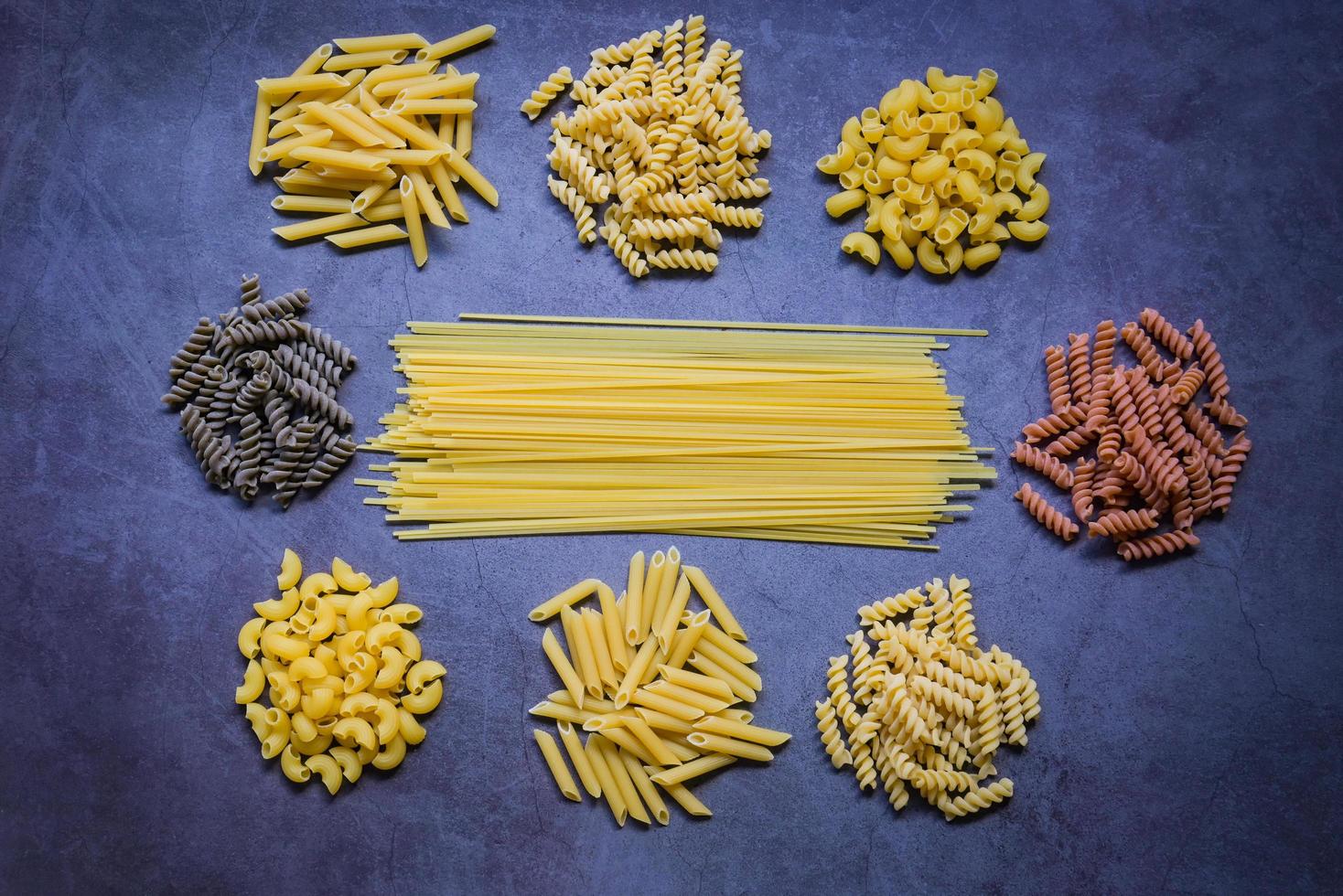 pasta cruda varios tipos de pasta cruda macarrones espaguetis y fideos en madera, concepto culinario de comida italiana, colección de diferentes pastas crudas en la mesa de cocina para cocinar comida foto