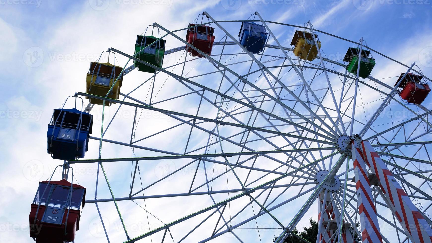 Colorful ferris wheels in the amusement park on a background of blue sky with clouds. Toned image. Bottom view photo