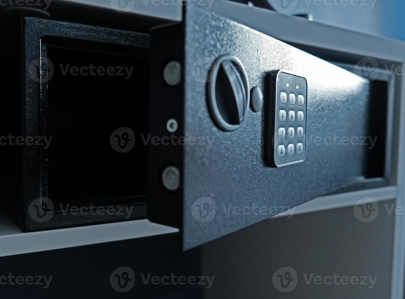 Metal safe box in the closet. Small narrow safe for keeping money or valuables in the hotel. Open safe door with buttons for entering a password. Compact strongbox inside cabinet. Empty safe. photo