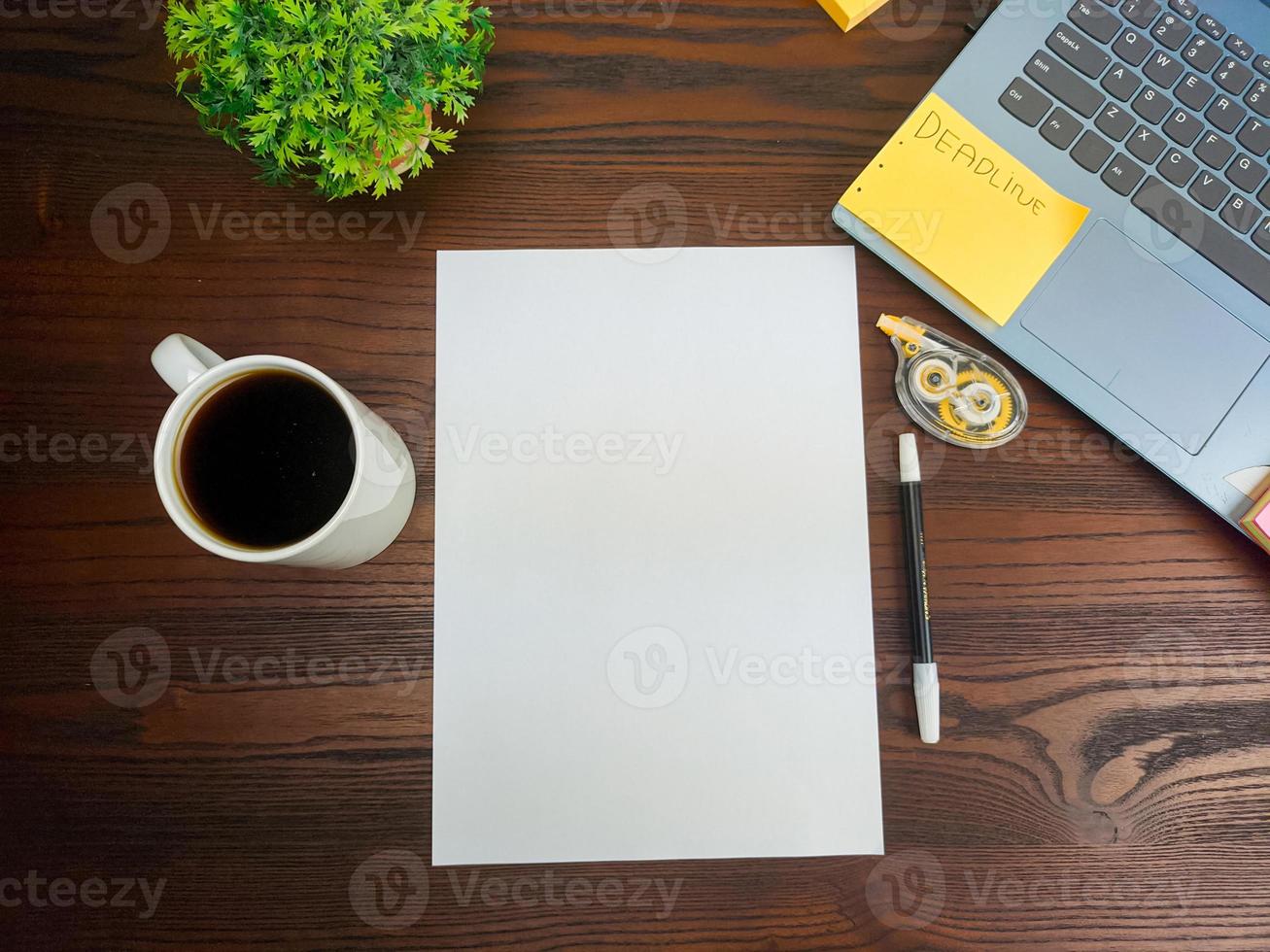 endecha plana, papel simulado. espacio de trabajo en el fondo del escritorio de la oficina desde la vista superior. con papel blanco en blanco, computadoras portátiles, útiles de oficina, lápices, hojas verdes y tazas de café en una mesa de madera. foto