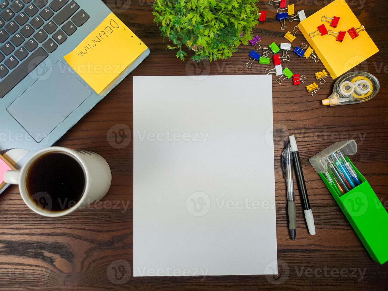 Flat lay, mock up paper. workspace in the background of the office desk from the top view.  with blank white paper, laptops, office supplies, pencils, green leaves, and coffee cups in a wooden table. photo