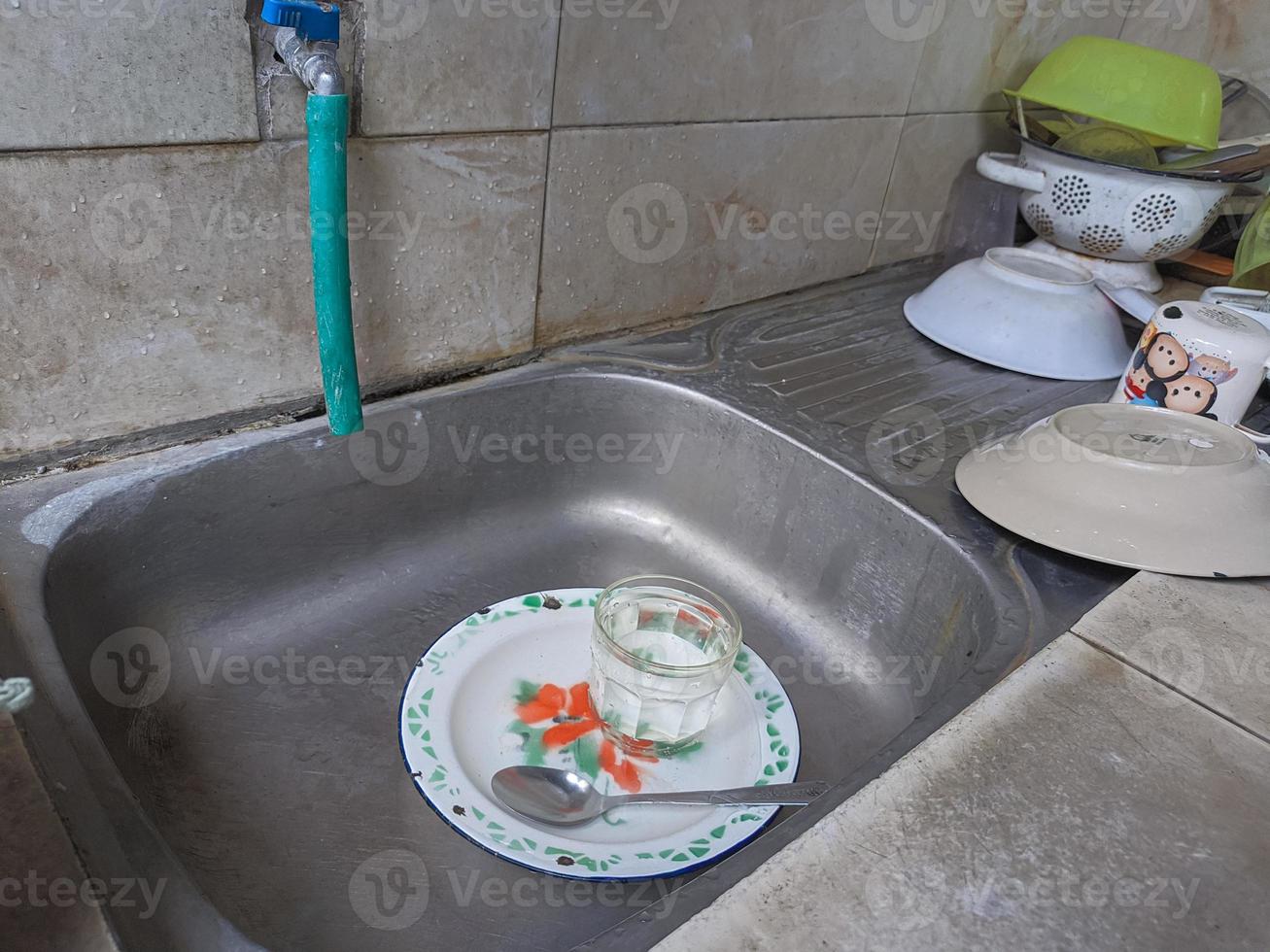 platos y vasos sucios en el fregadero que no han sido lavados. montones de platos sucios y vasos que no han sido lavados, la vida real al final del año foto