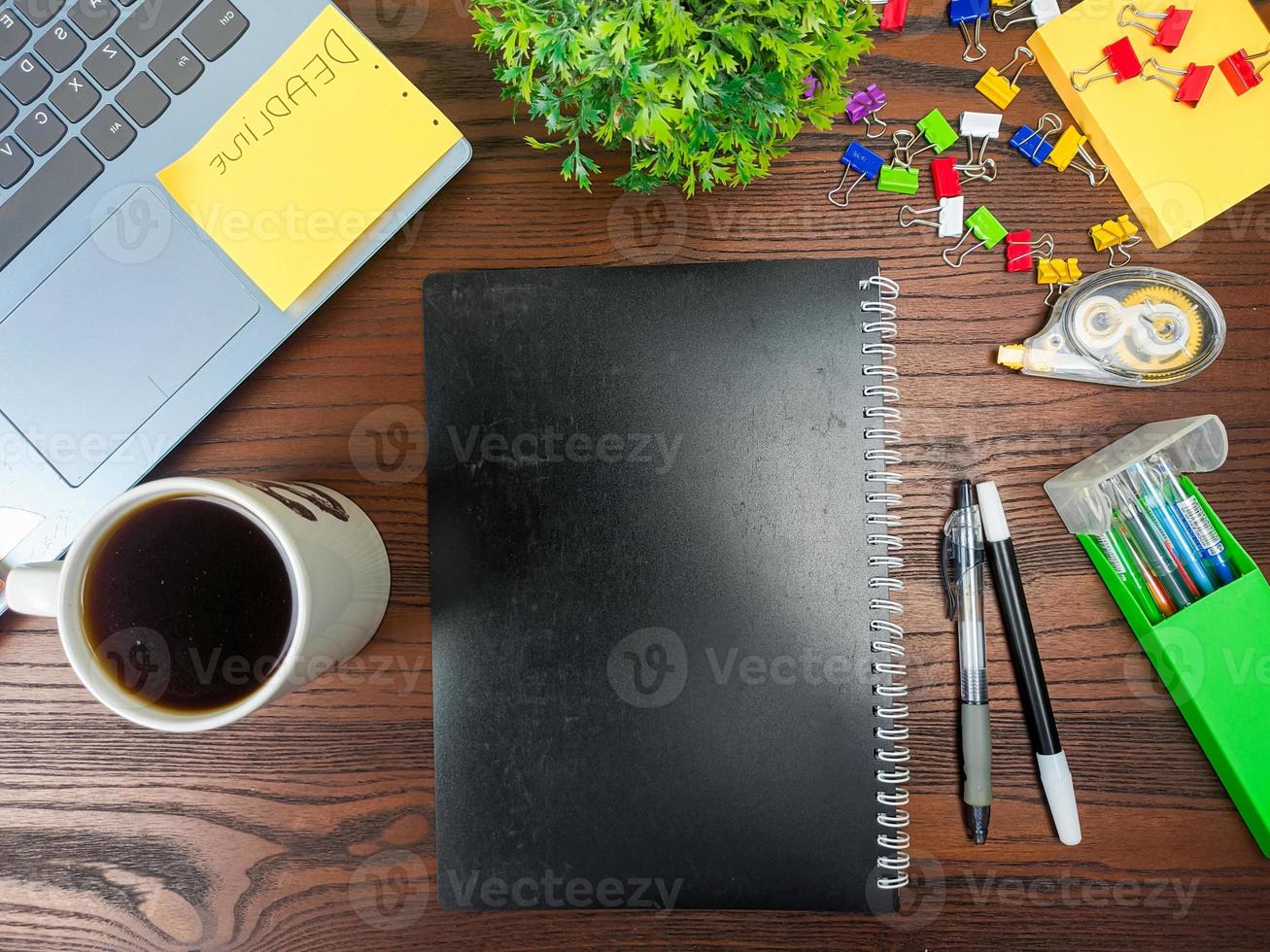 Flat lay, black book mock up. workspace in the background of the office desk from the top view. with black books, laptops, office supplies, pencils, green leaves, and coffee cups in the wooden table. photo