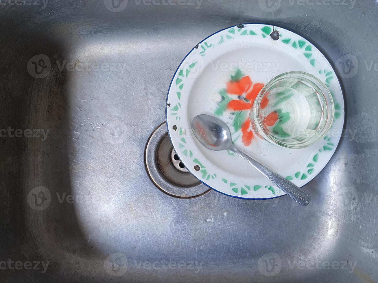 Dirty dishes and glasses in the sink that have not been washed. Piles of dirty dishes and glasses that haven't been washed, real life at the end of the year photo