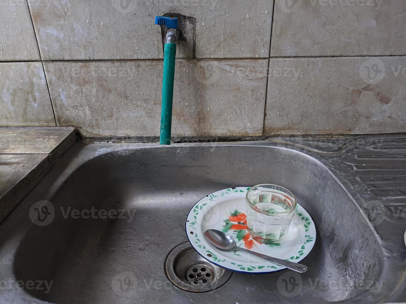 Dirty dishes and glasses in the sink that have not been washed. Piles of dirty dishes and glasses that haven't been washed, real life at the end of the year photo